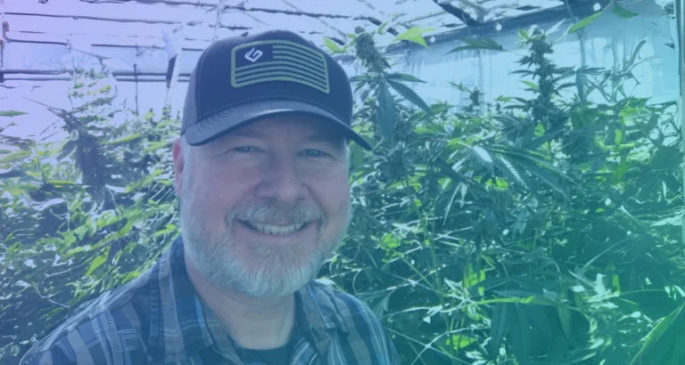 Lance Lambert, CMO von Grove Bags, vor Cannabispflanzen in einer Anbauanlage