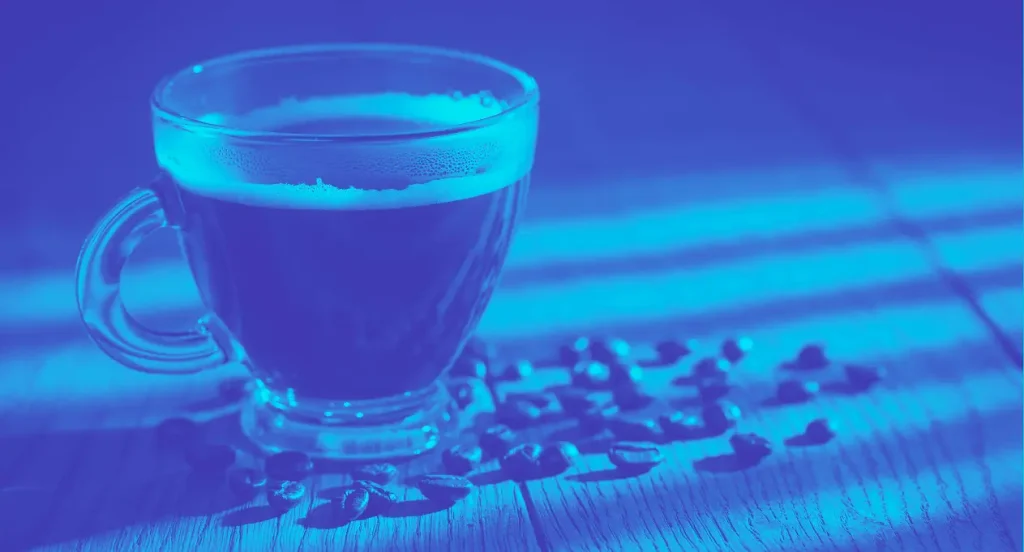 a cup of coffee with coffee beans on the table