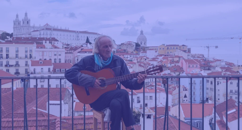 man playing guitar with a view of lisbon portugal behind him